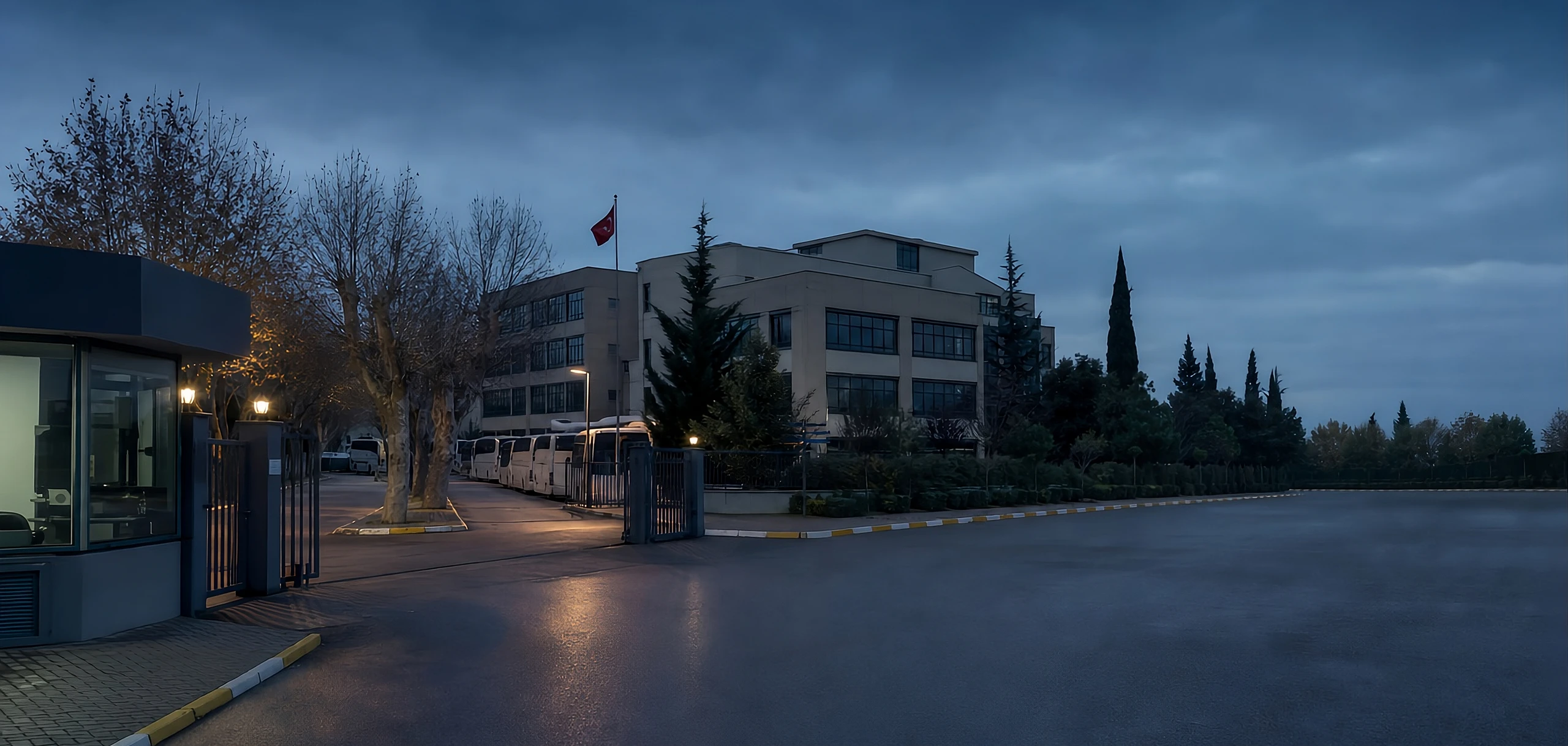 Alacakaranlıkta bir okul binası; giriş kapısı ve bahçe aydınlatması yanıyor.